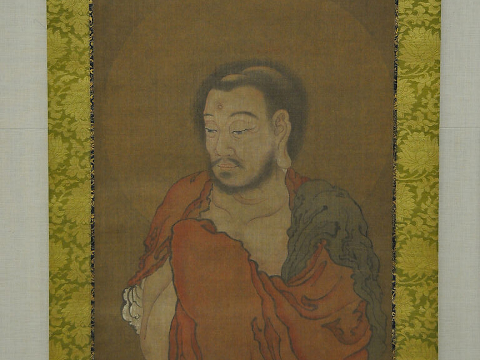 Shakyamuni steps down from the mountains in a fifteenth-century Japanese hanging scroll, wrapped in layered red and grey robes.