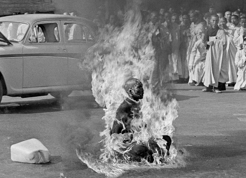 Black-and-white photograph of Buddhist monk Thích Quảng Đức seated in flames on a Saigon street while other monks watch.